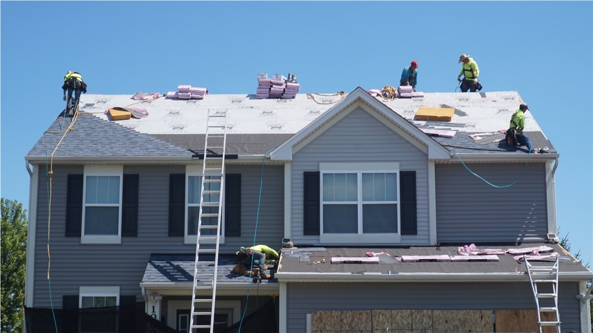 Expert Cedarline Roofing technician inspecting a newly installed roof in Midland, TX for quality assurance and durability, Crew on the roof of a two-story gray home with a ladder in place during residential roofing in Gardendale - TX