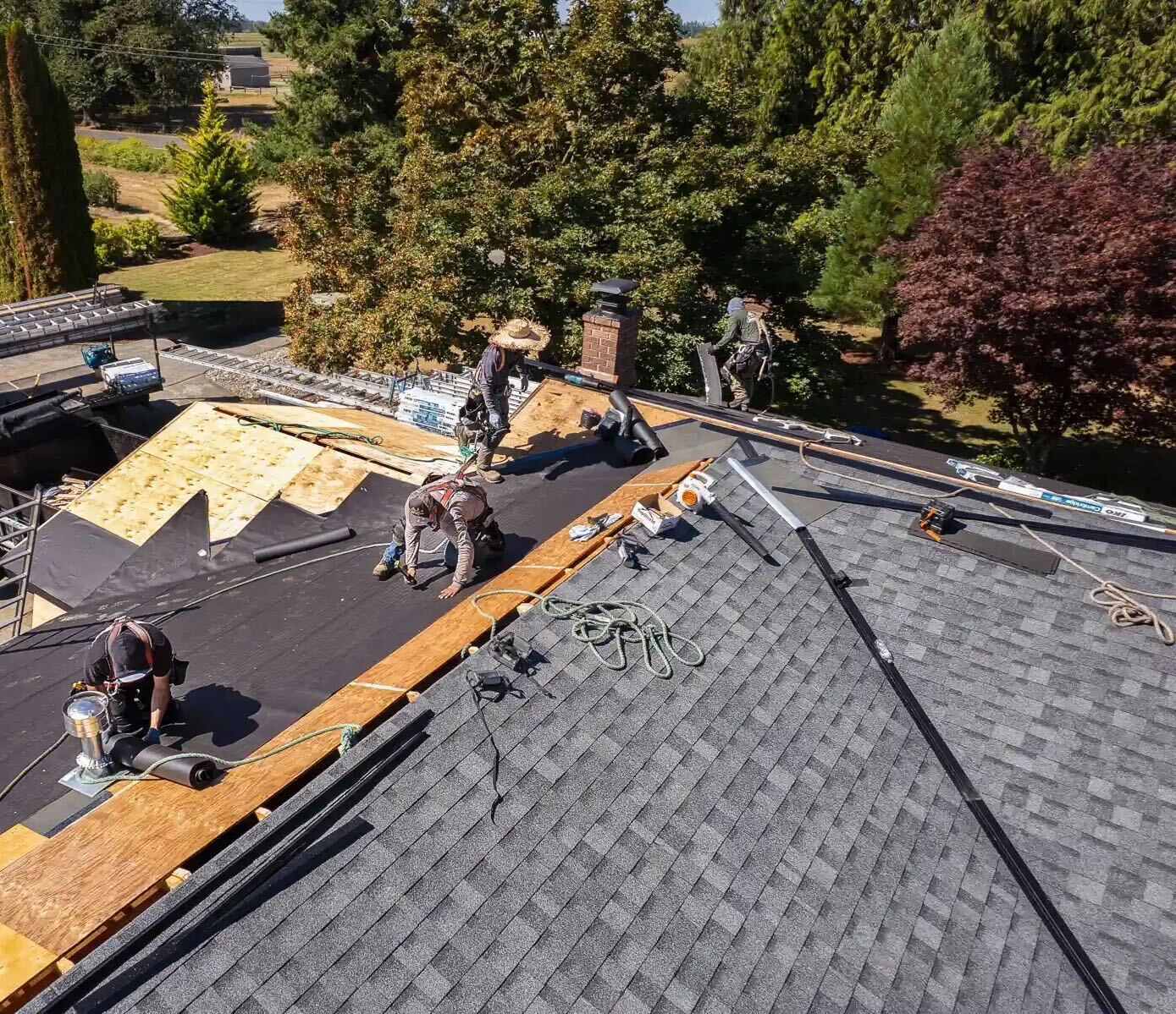 Crew replacing worn shingles on a ranch home under clear Texas skies