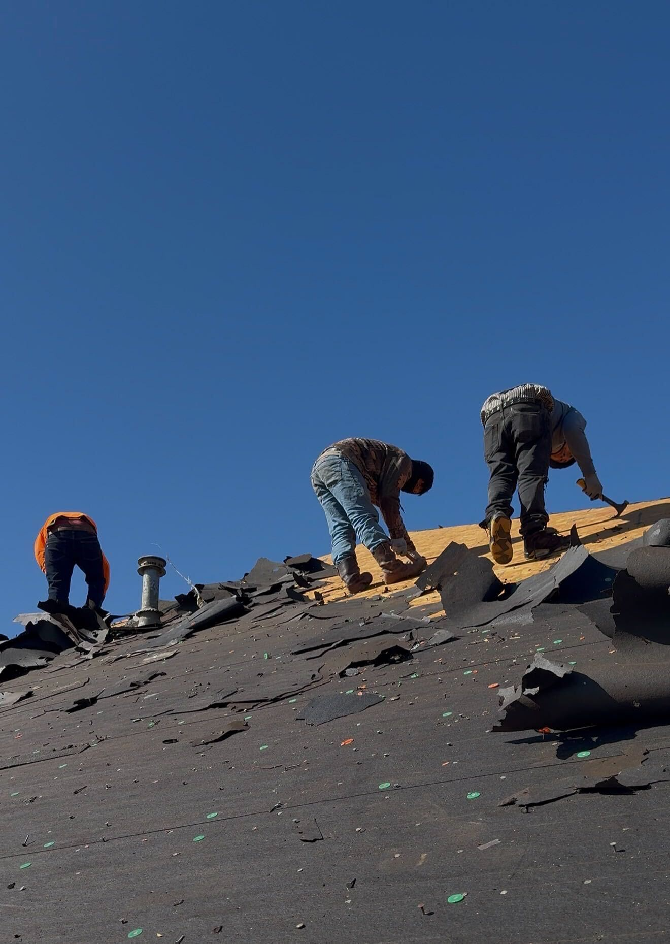 Roofing professional examining underlayment and flashing during full replacement project
