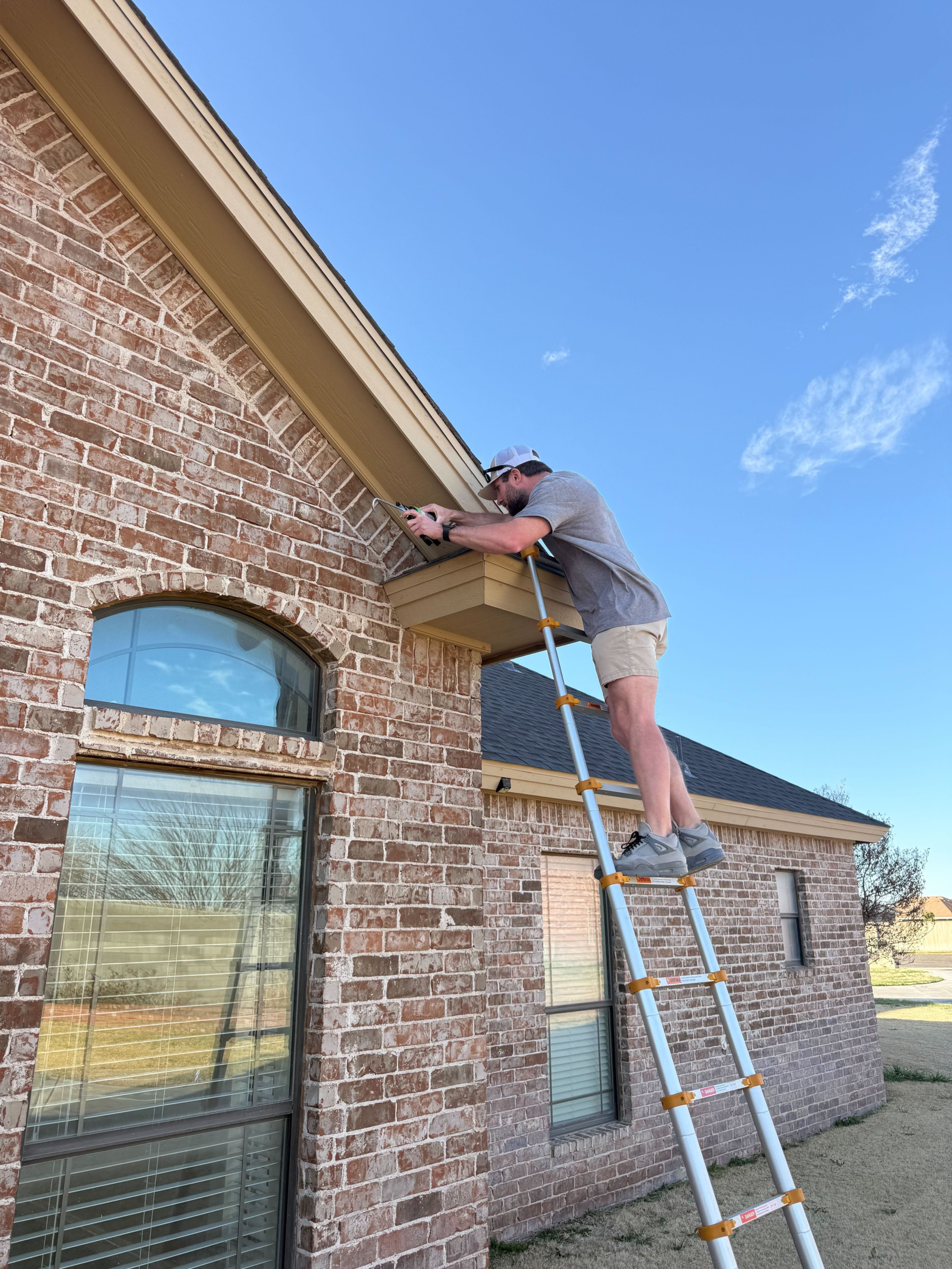 Experienced roofer inspecting flashing and shingle alignment with precision tools on residence