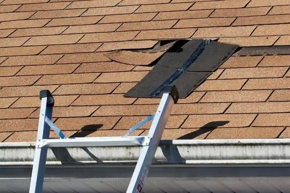Roofing crew replacing worn shingles on Midland home after wind and heat damage